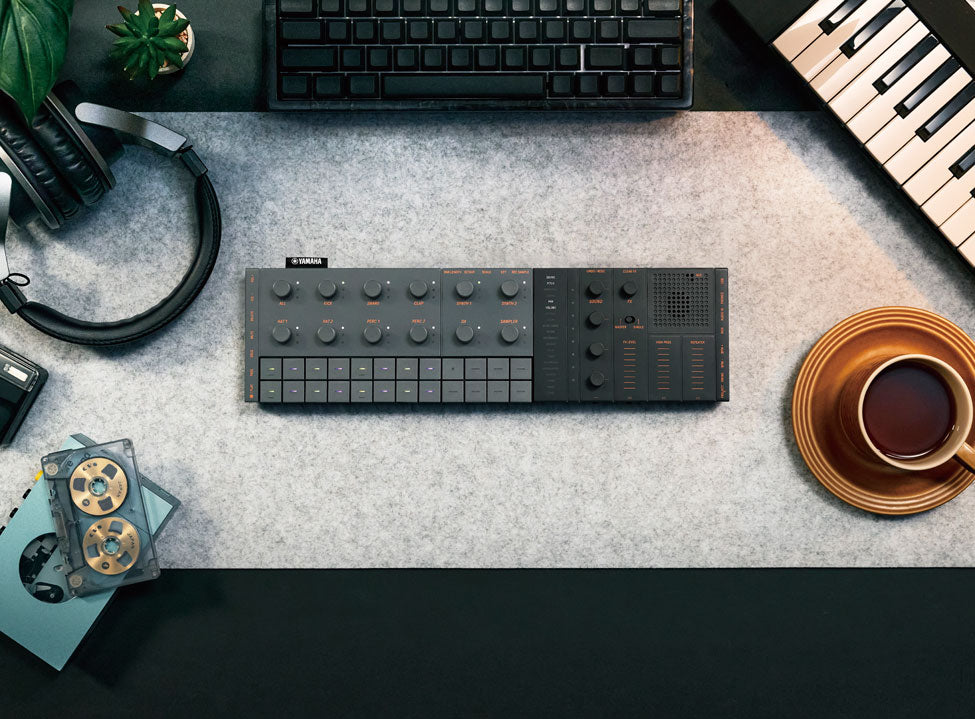 Yamaha Seqtrak viewed from above, placed on a desk in front of a computer, with headphones and a MIDI keyboard nearby.